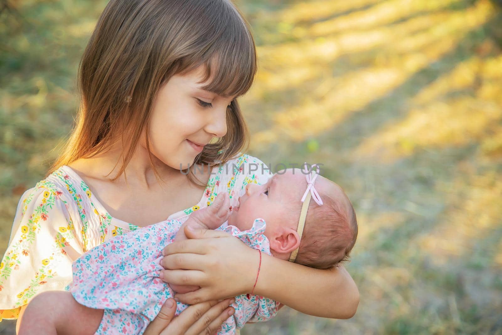 The older sister holds the newborn in her arms. Selective focus. by yanadjana