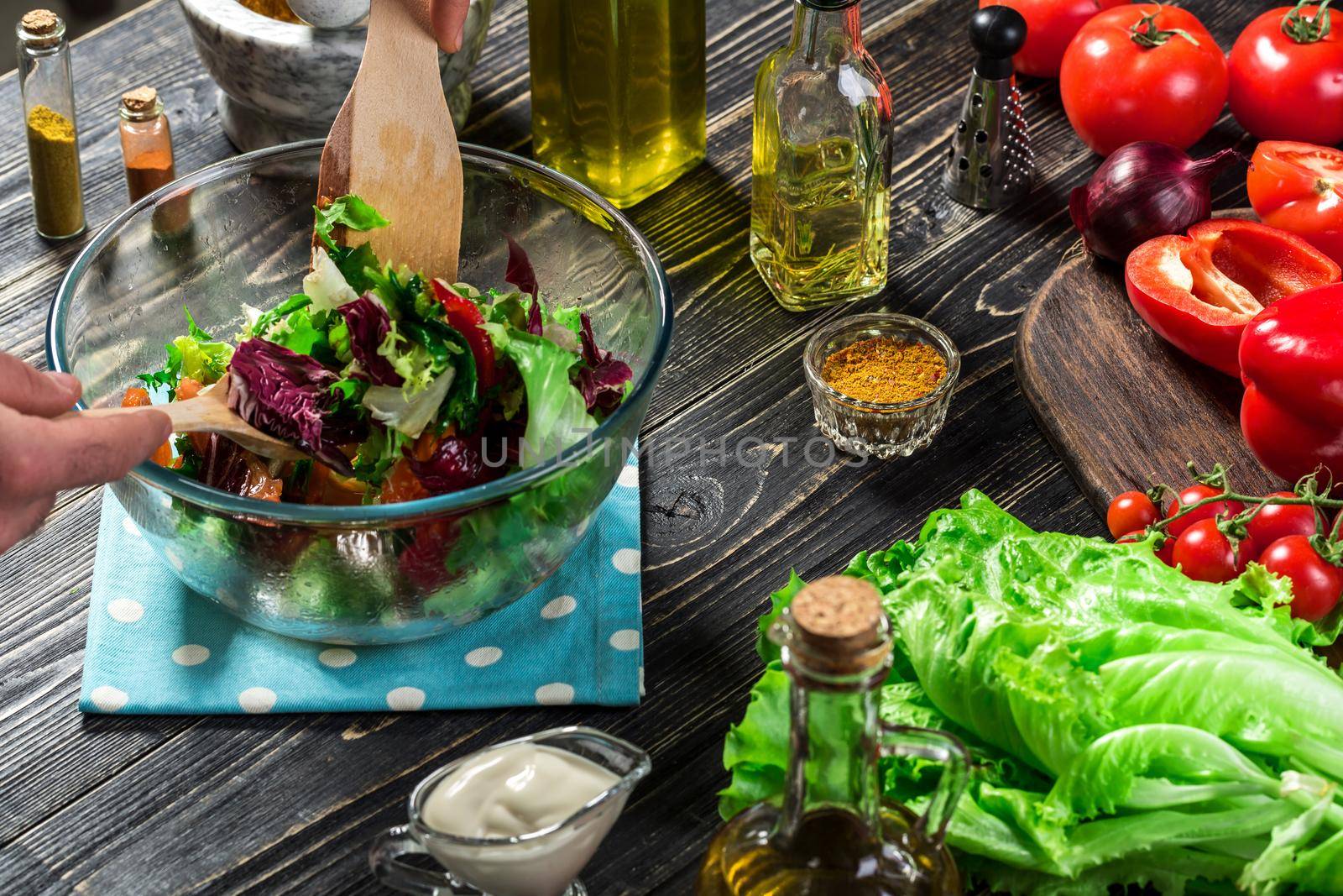 Man preparing salad with fresh vegetables on a wooden table. Cooking tasty and healthy food. Close-up by nazarovsergey