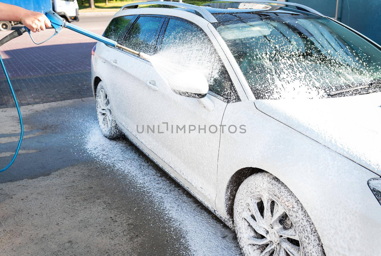 Hand washing with high pressure water in a car wash outside. A jet of foam. The concept of hand washing, self-service. by sfinks