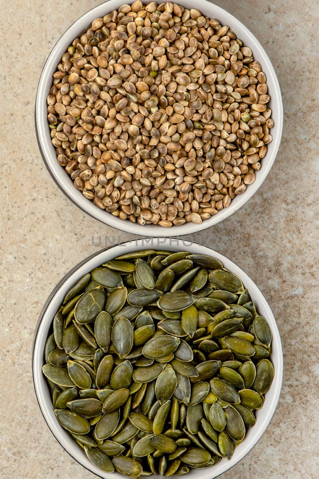 Superfoods, hemp seeds and pumpkin seeds in a saucer on a marble top