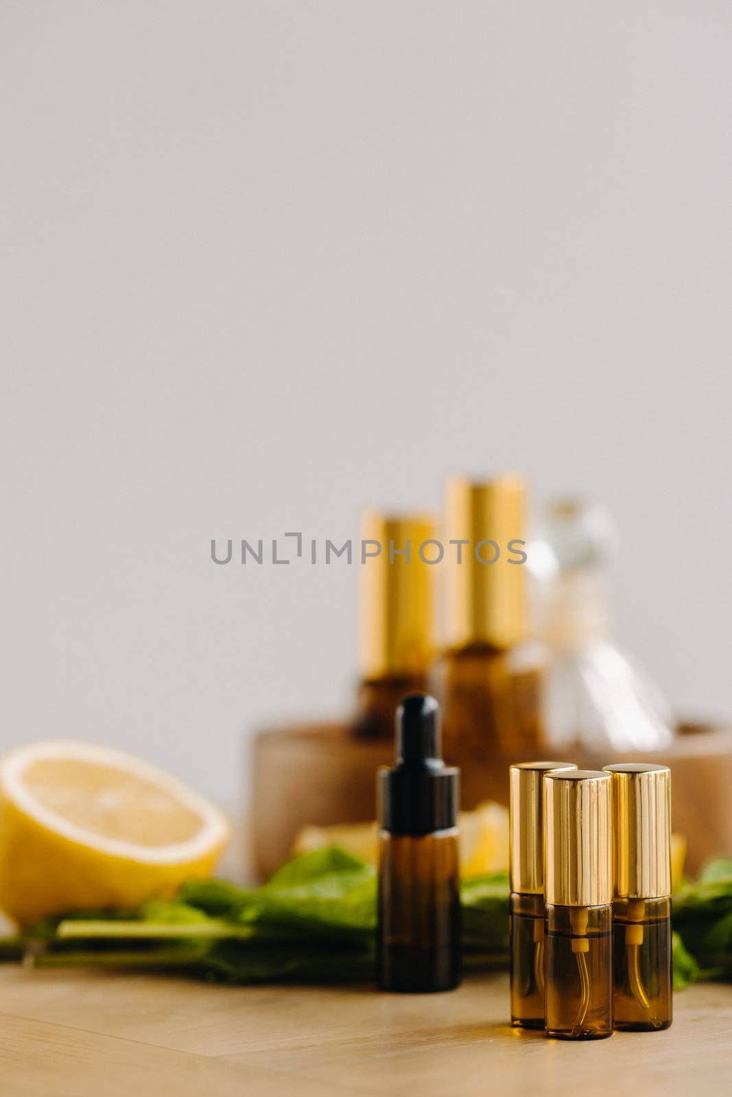 Essential oil in bottles with lemon and mint fragrance lying on a wooden surface by Lobachad