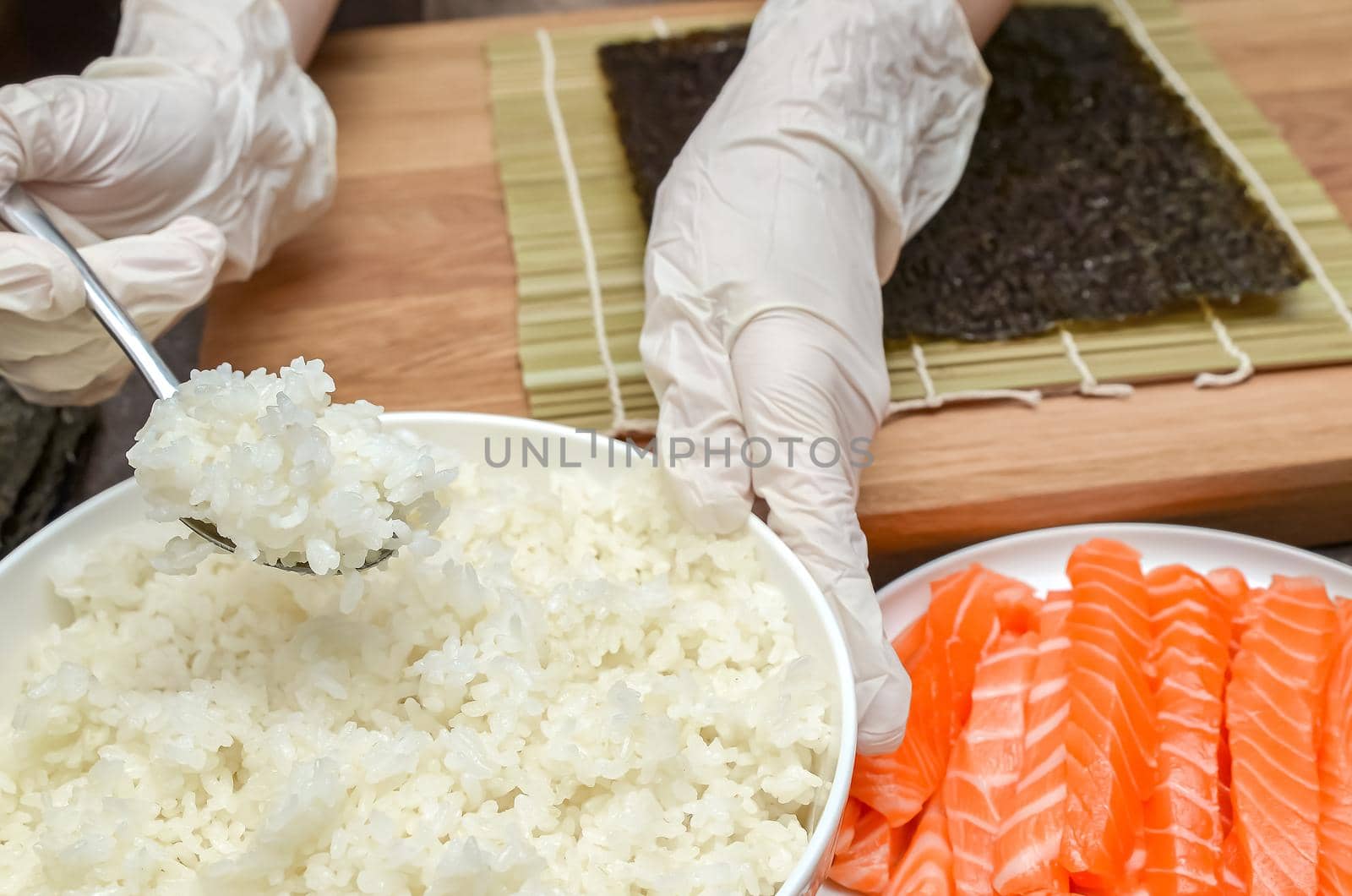 Using rice for sushi, the process of making sushi with salmon and avocado.
