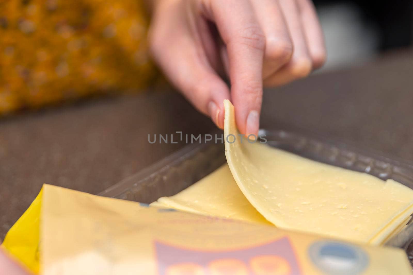 Opens a bag of sliced cheese, a woman opens a bag of cheese, pieces of cheese in a bag.