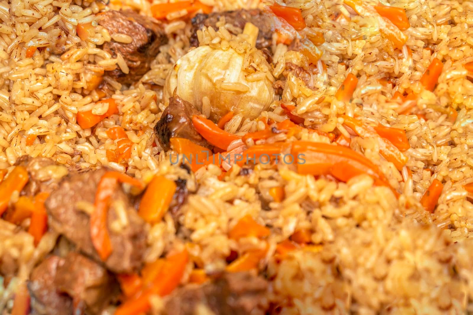 Pilaf close-up. Oriental cuisine concept. National Uzbek pilaf with meat in a cast-iron pan. Top view, lamb, devzira rice,garlic.