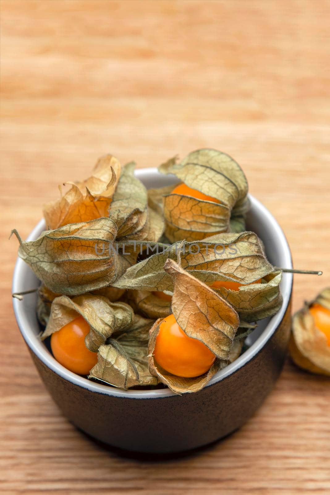 Physalis fruits on a wooden table. Sweet yellow physalis berries in a cup on wood background by SERSOL