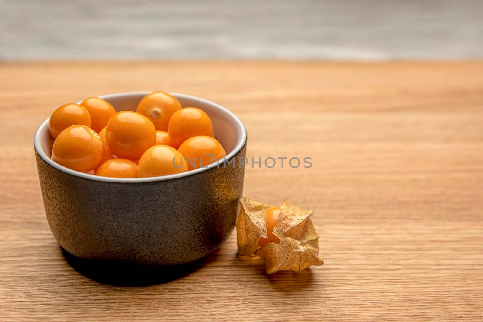 Physalis fruits on a wooden table. Sweet yellow physalis berries in a cup on wood background.