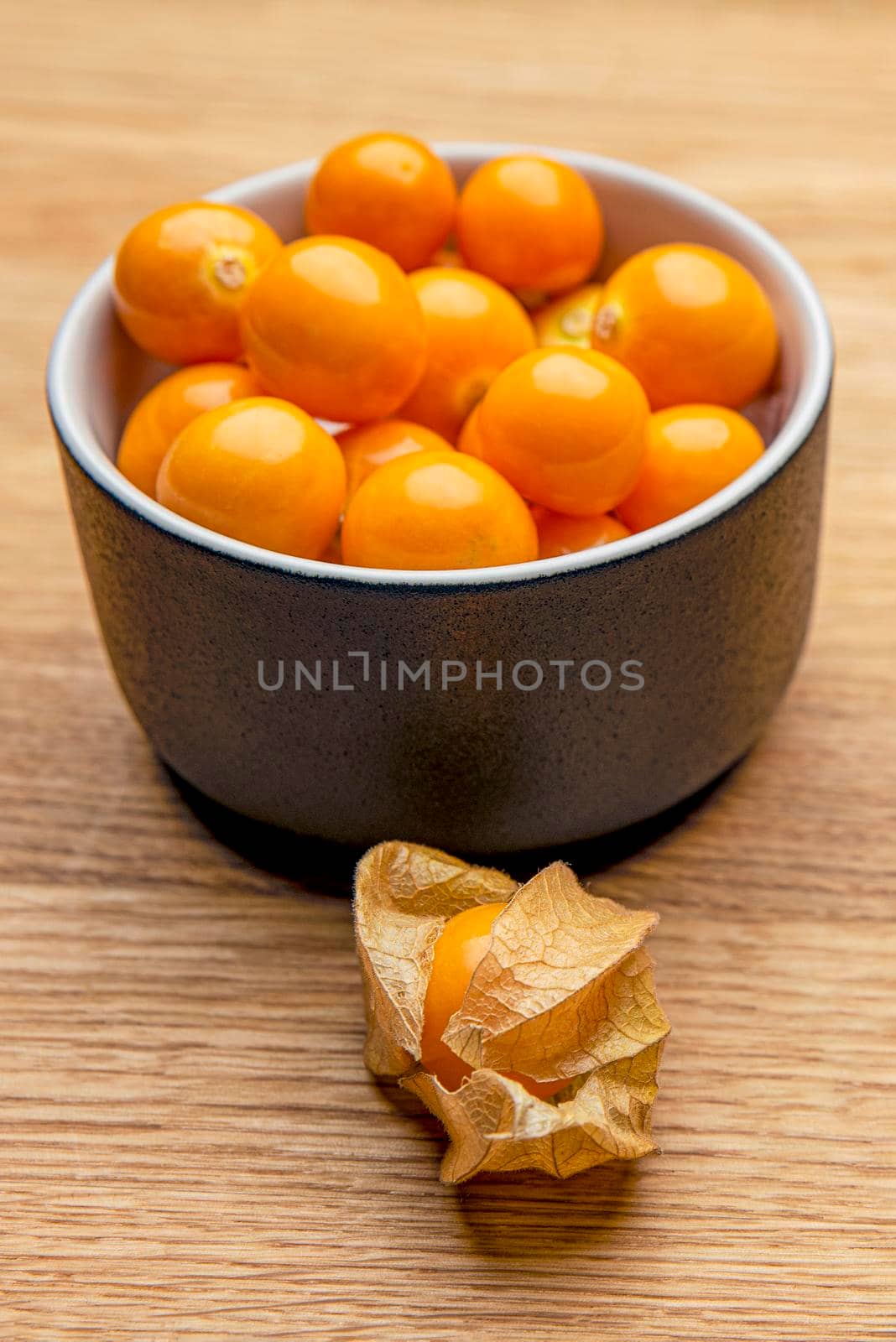 Physalis fruits on a wooden table. Sweet yellow physalis berries in a cup on wood background.