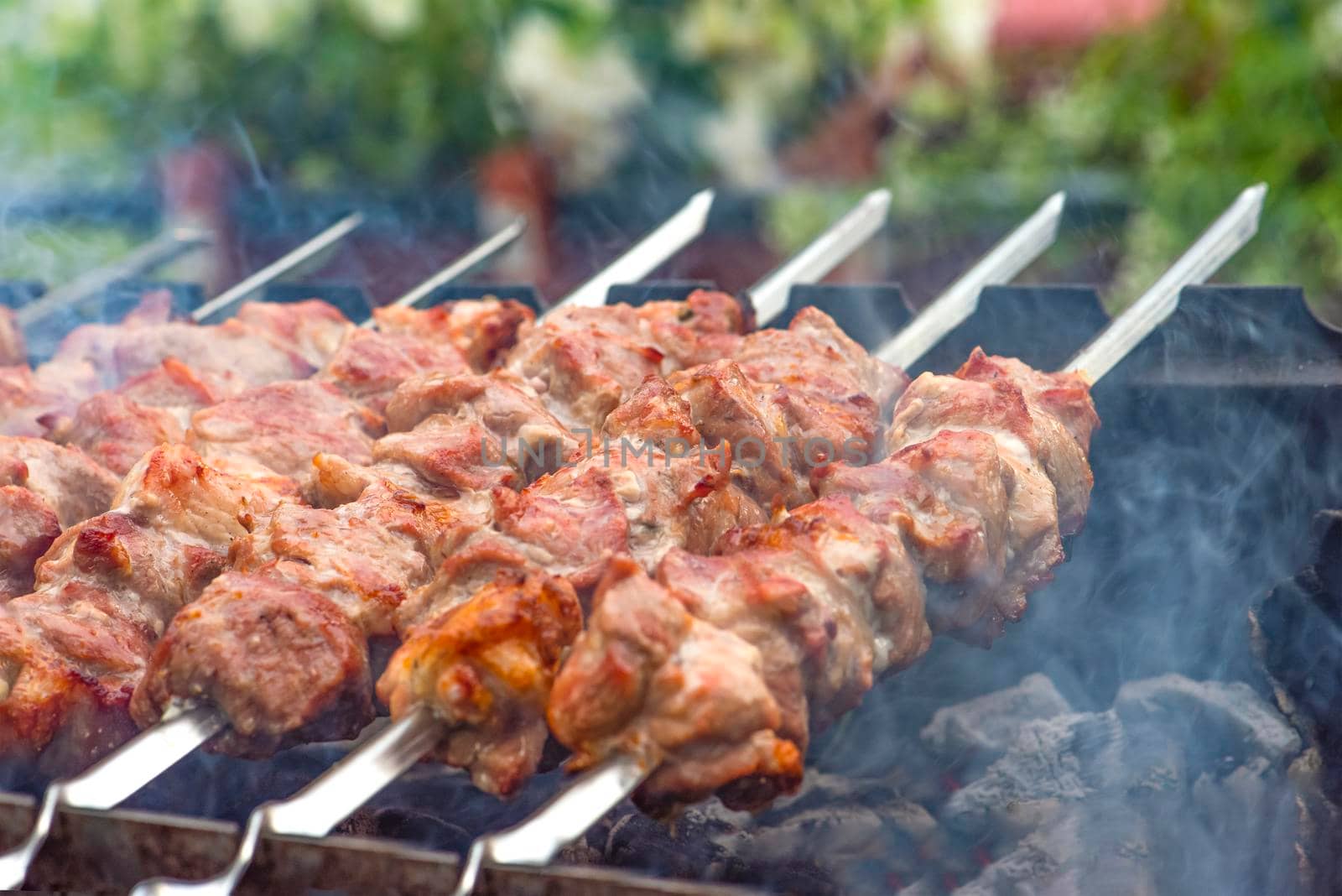 Cooking barbecue, grilled meat barbecue. Cooking pork shashlik on metal skewers. Smoke from embers builds up over the dish. Advertising banner with copy space.