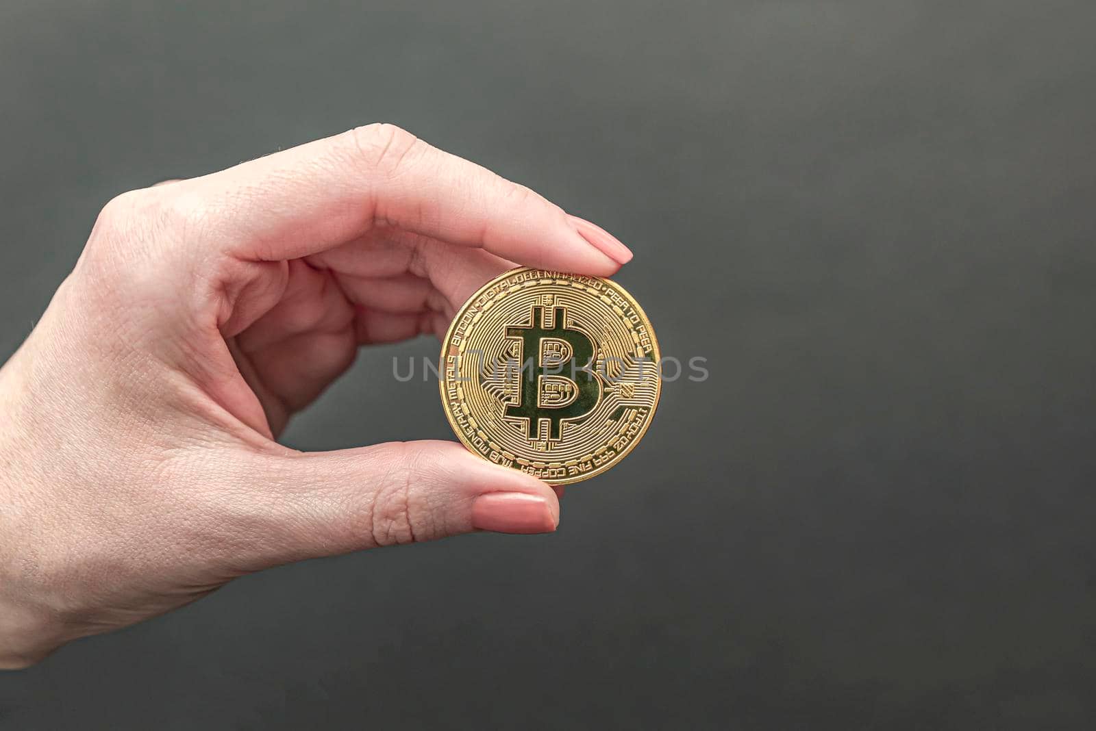 bitcoin in hand, female hand holds a gold bitcoin coin. Cryptocurrency value, digital money, space for text. Blue background