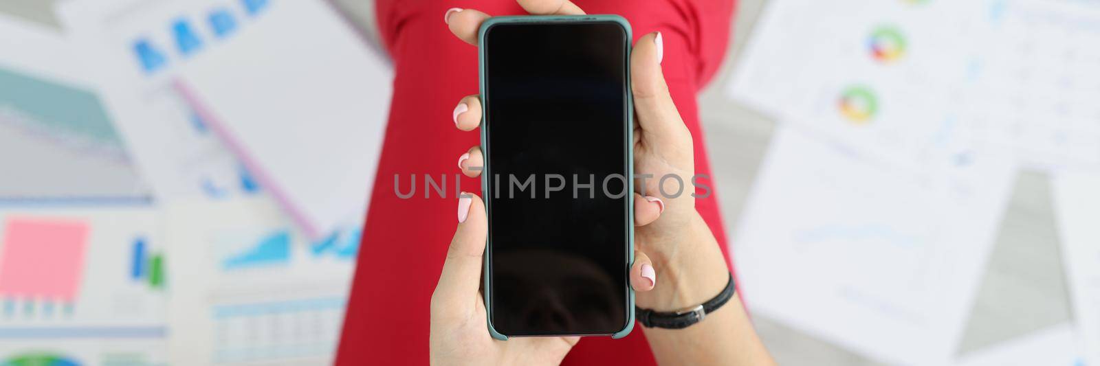 Top view of woman holding phone with black screen, turn off device, no connection, broken smartphone, mockup. Technology, work collapse, damage concept. Copy space. Blurred background