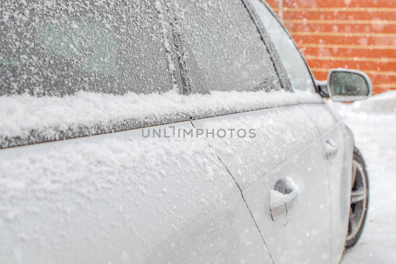 Frozen rearview mirror, snowy car. Winter snow snowfall.