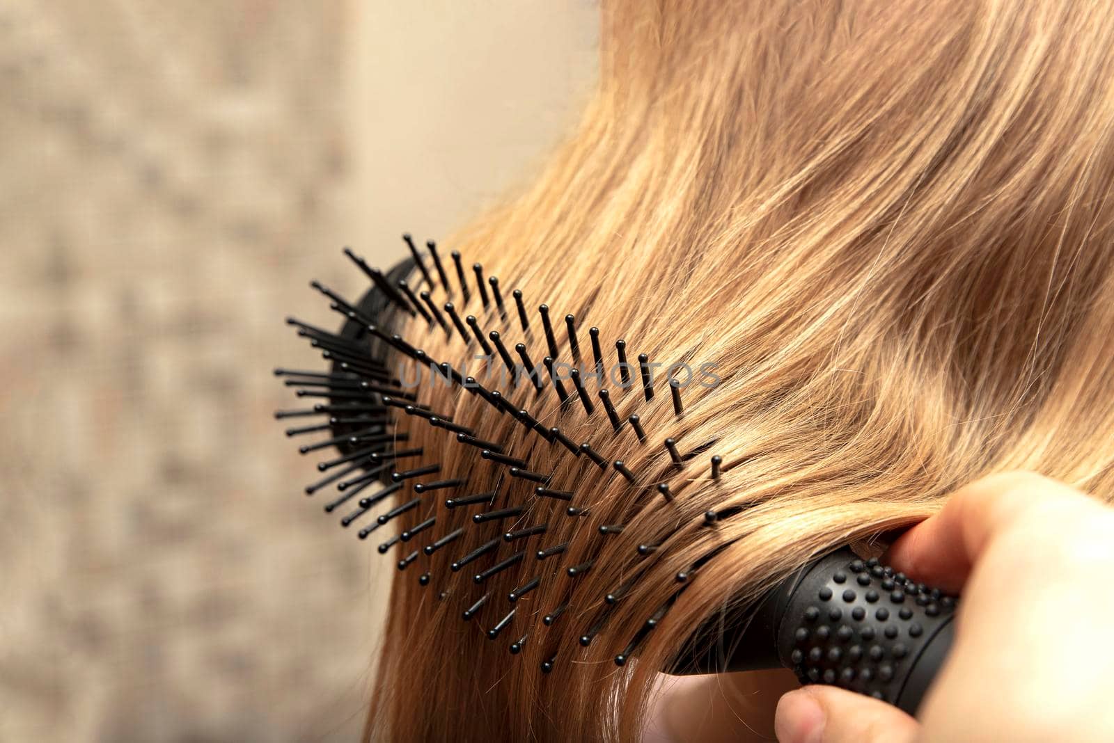 The girl combs her hair with a comb in the bathroom. Place for your text. Home hair care concept.