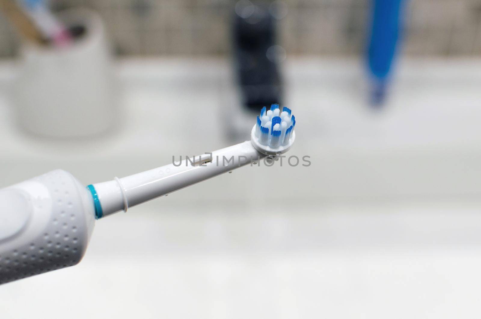 Rechargeable, electric toothbrush, close-up. Against the backdrop of a bathroom in white. by SERSOL