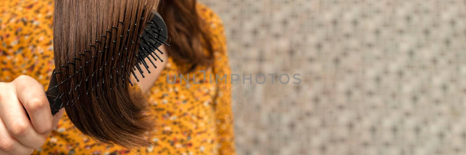 The girl combs her hair with a comb in the bathroom. Place for your text. Home hair care concept