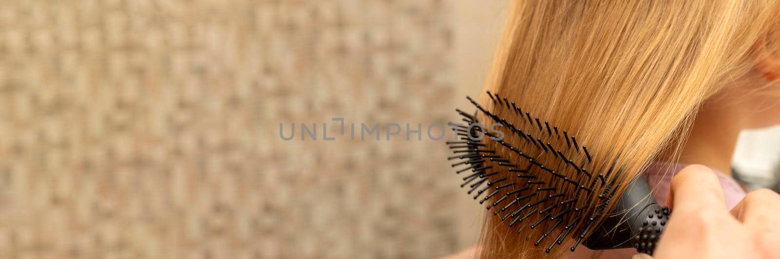 The girl combs her hair with a comb in the bathroom. Place for your text. Home hair care concept