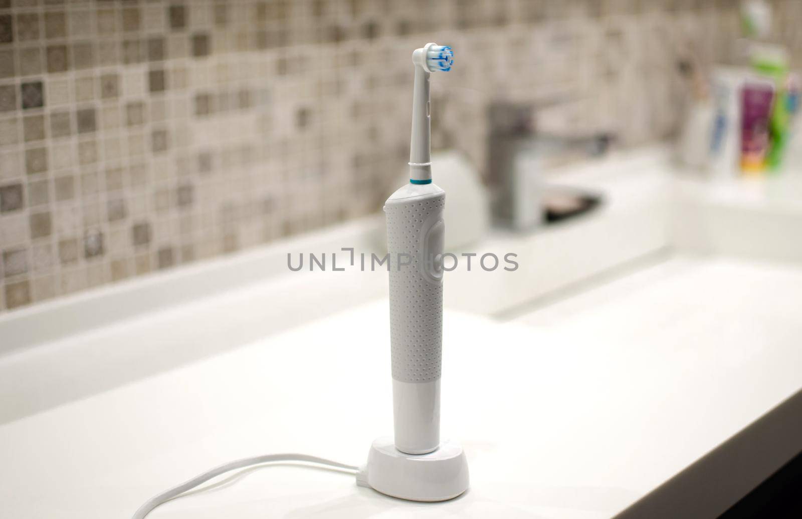 Rechargeable, electric toothbrush, close-up. Against the backdrop of a bathroom in white. by SERSOL