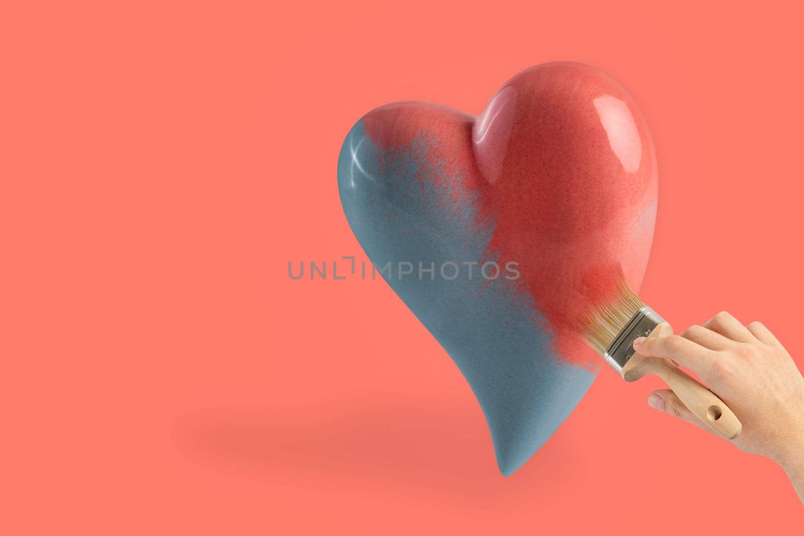 Pink heart on a pink background. A man's hand paints a black and white heart in pink with a brush with pink paint. Valentine's day concept