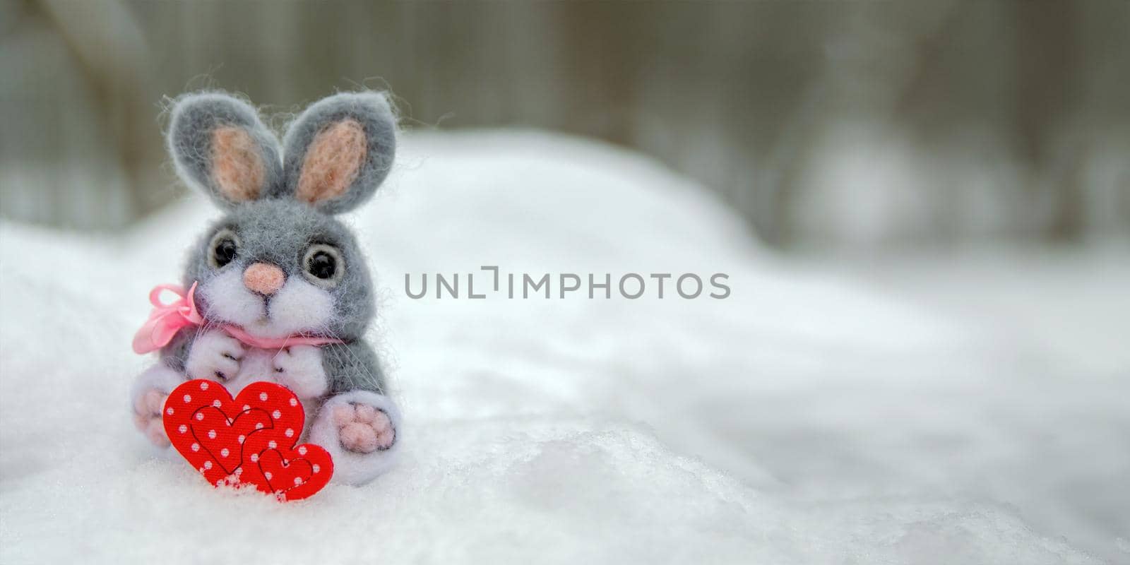 Happy Valentine's Day greeting card or banner. Plush rabbit holding a red heart symbol of love. Holidays Happy Valentine's Day