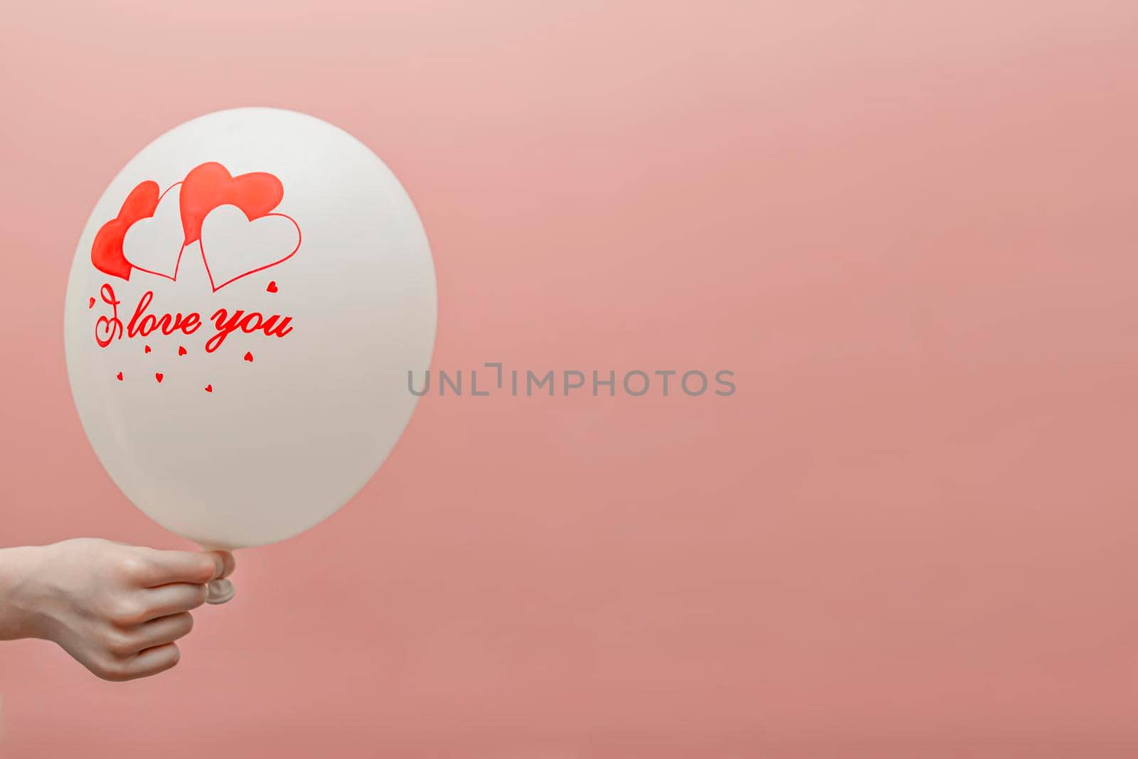 Valentine's card with place for text. Balloon with the inscription love in the child's hand. On a pink background.