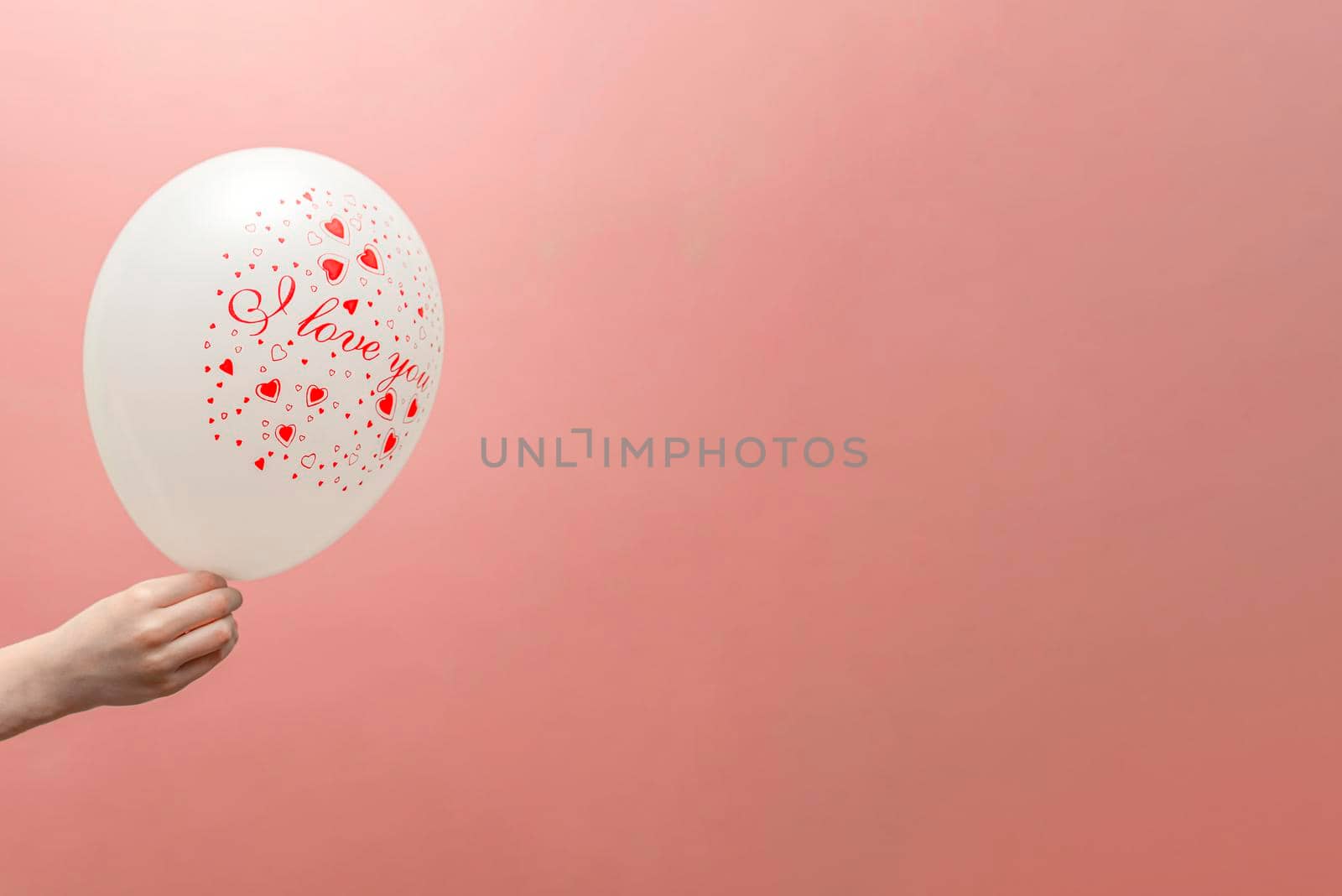 Valentine's card with place for text. Balloon with the inscription love in the child's hand. On a pink background.