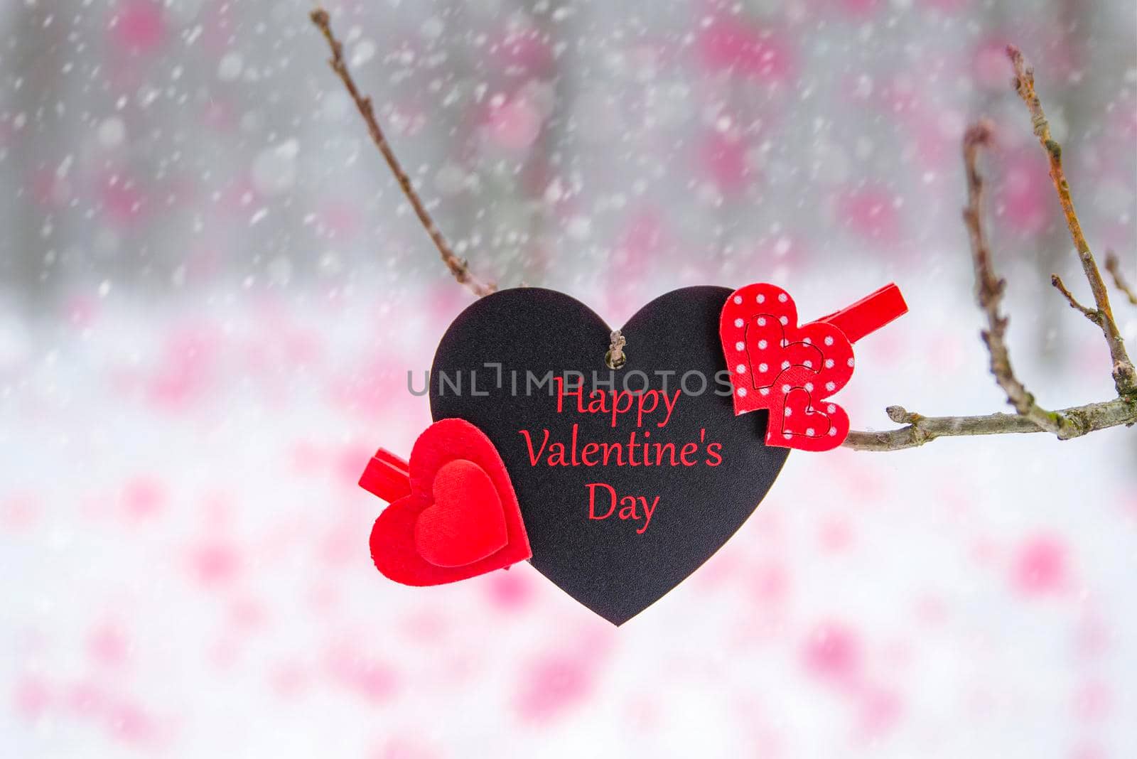 Happy Valentine's Day greeting card or banner. Red hearts on a branch of a snow-covered tree in winter. Holidays Happy Valentine's Day. Snowfall on the background of the forest.