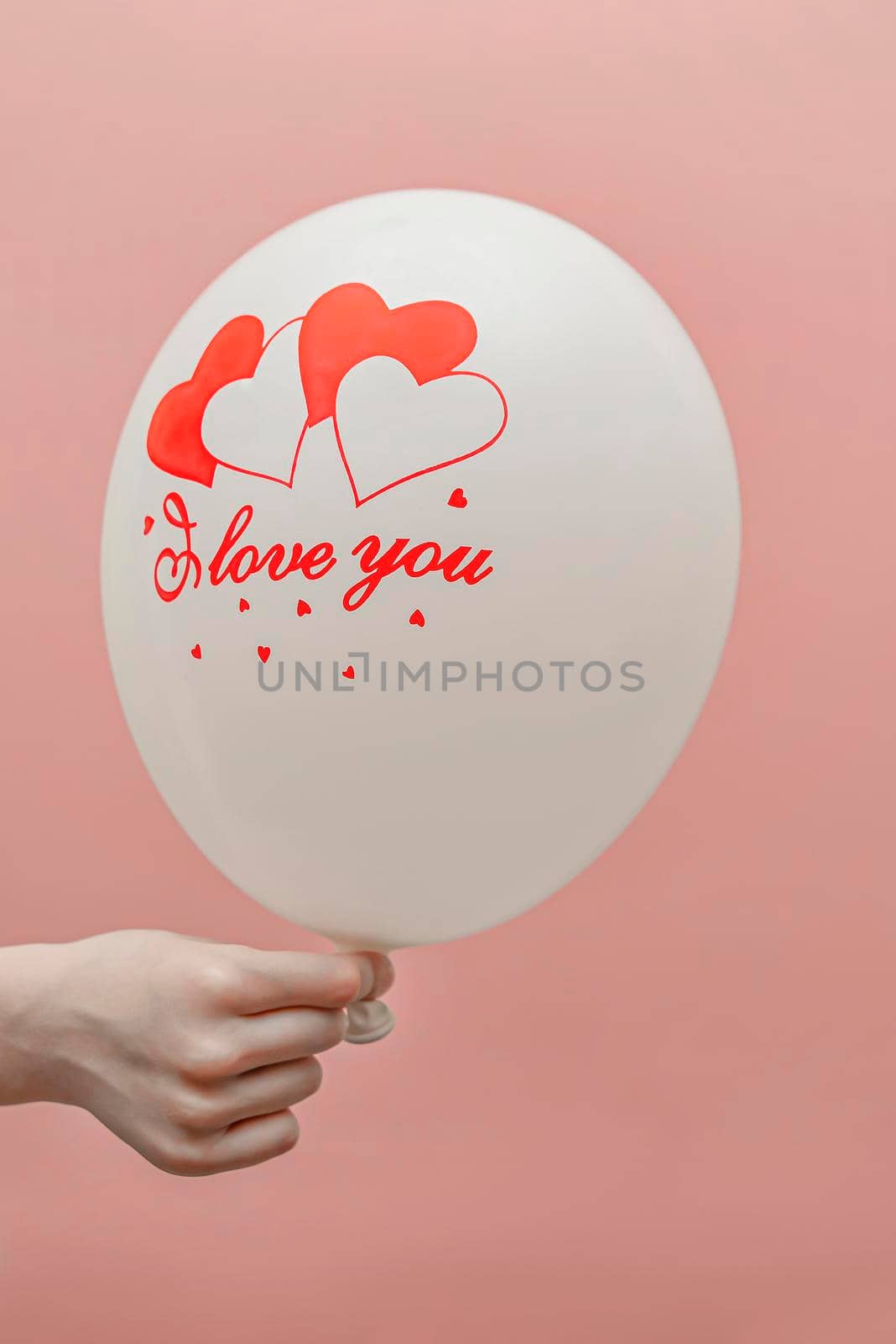 Valentine's card with place for text. Balloon with the inscription love in the child's hand. On a pink background.