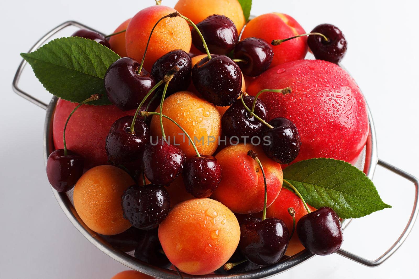 apricots and cherries in a metal bowl on a white background. Close-up by lara29