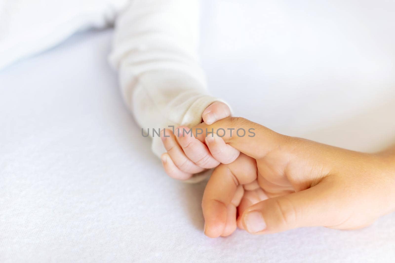 Newborn toddler holds his sister's hand. Selective focus. People.