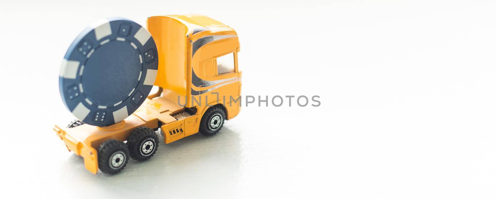 a toy truck with a poker chip on white background.