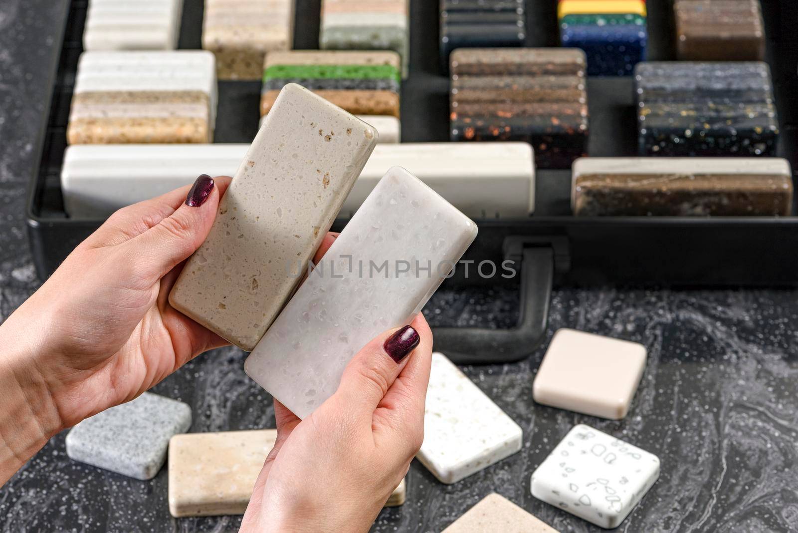 Samples of material for the countertop. Female hands are choosing interior elements for renovation. Samples of acrylic stone in hands