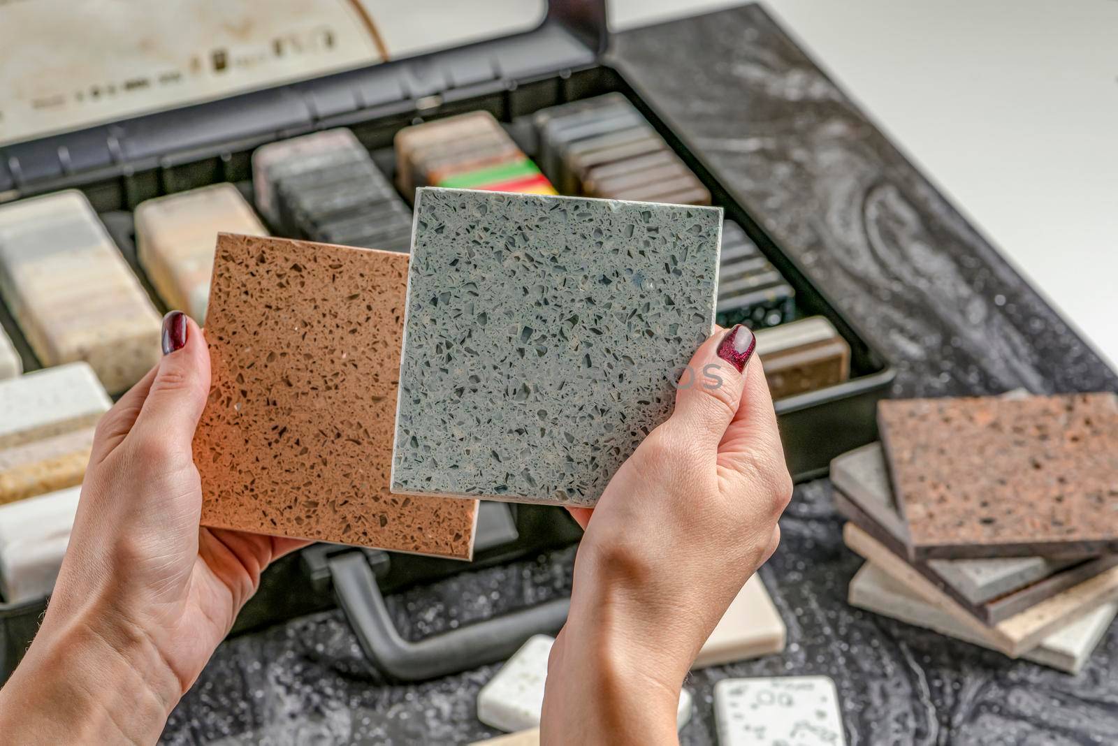 Samples of material for the countertop. Female hands are choosing interior elements for renovation. Samples of acrylic stone in hands