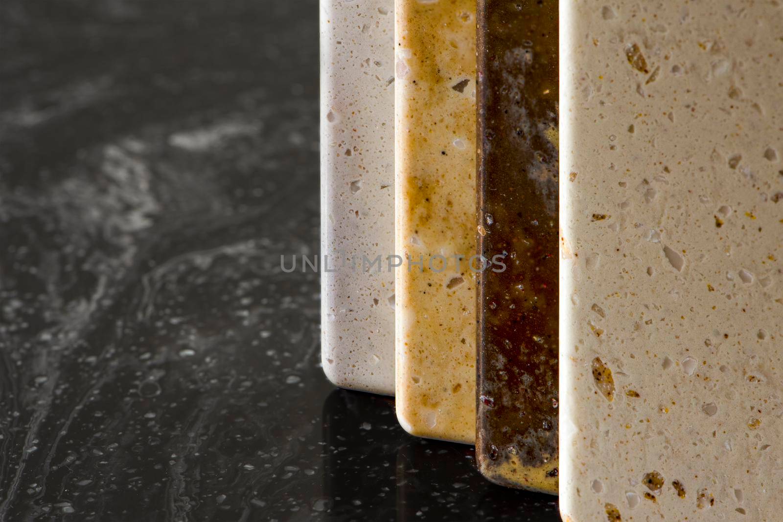 Large selection of stone samples for countertops and floors. Pieces of artificial acrylic stone in a sample box. A set of shades of countertops of different textures.