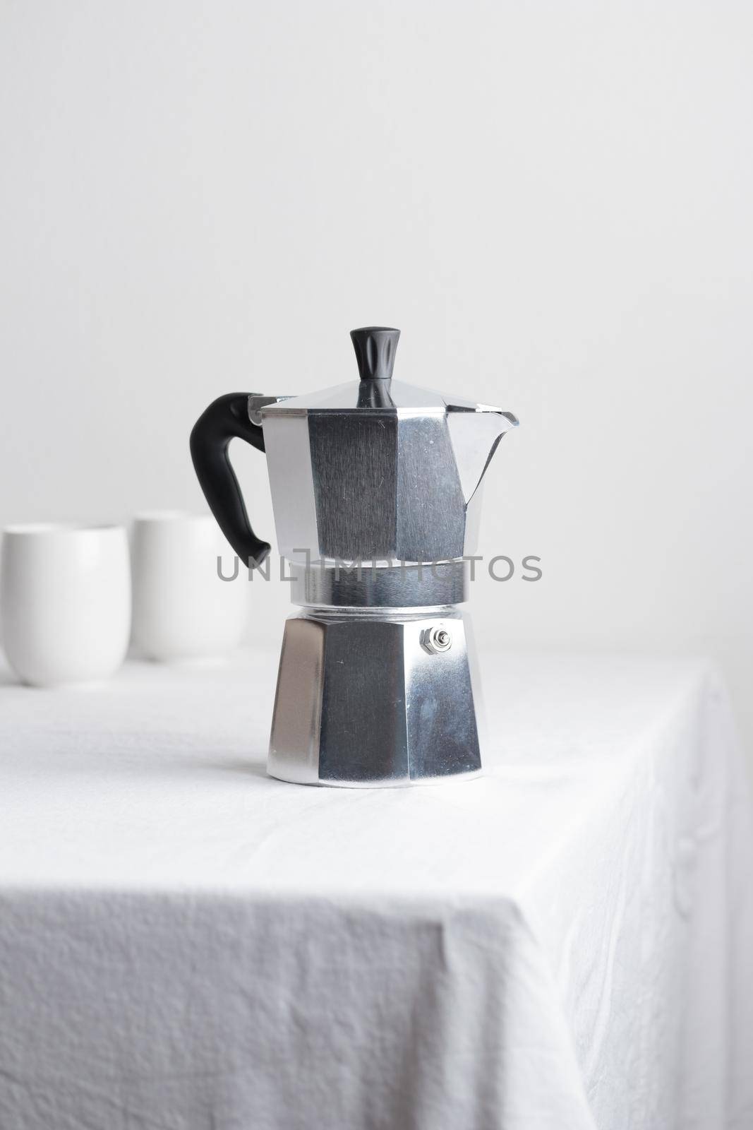 Classic aluminium coffee maker on white table with coffee space