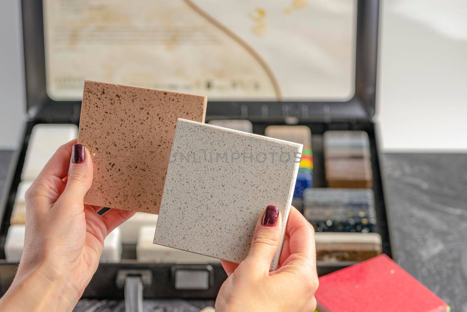 Samples of material for the countertop. Female hands are choosing interior elements for renovation. Samples of acrylic stone in hands