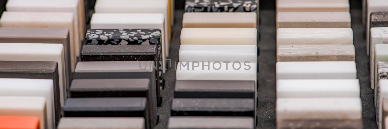 Large selection of stone samples for countertops and floors. Pieces of artificial acrylic stone in a sample box. A set of shades of countertops of different textures.