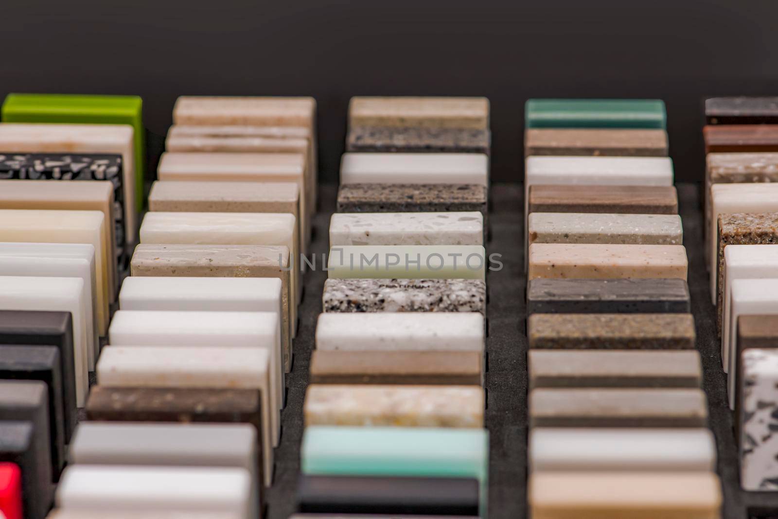 Large selection of stone samples for countertops and floors. Pieces of artificial acrylic stone in a sample box. A set of shades of countertops of different textures.