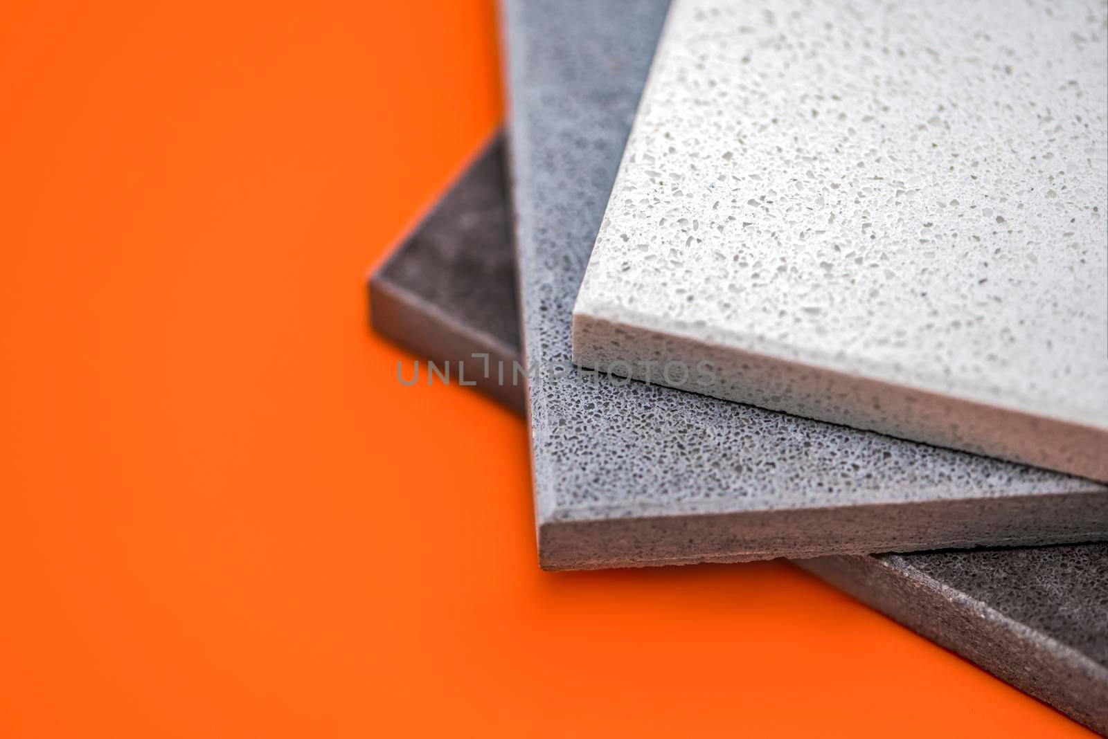 Samples of natural stone for kitchen countertops and floor tiles. Stone samples for countertops on orange background, copy space for design or text.