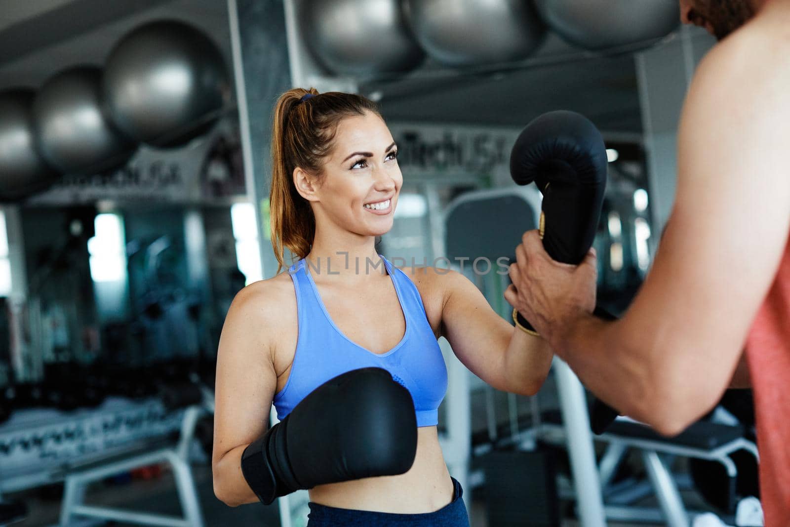 Portrait of healthy fit woman at the gym aupprted by a trainer exercising boxing