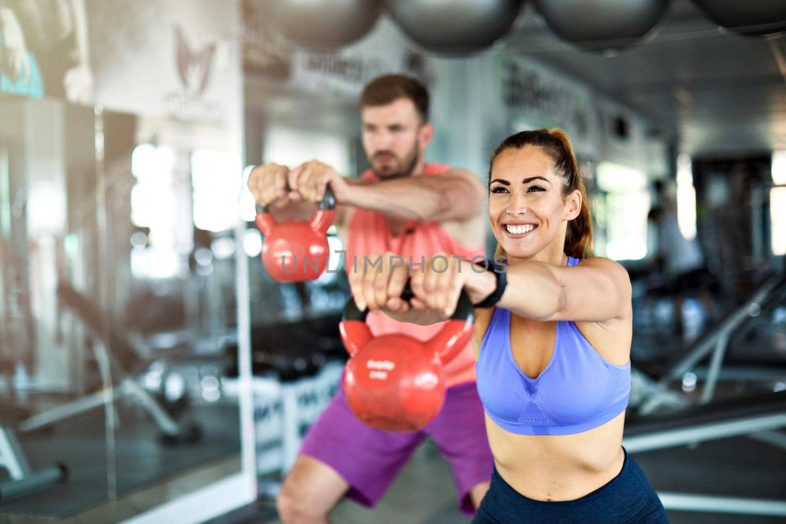 Happy healthy fit people at the gym exercising lifting kettlebell