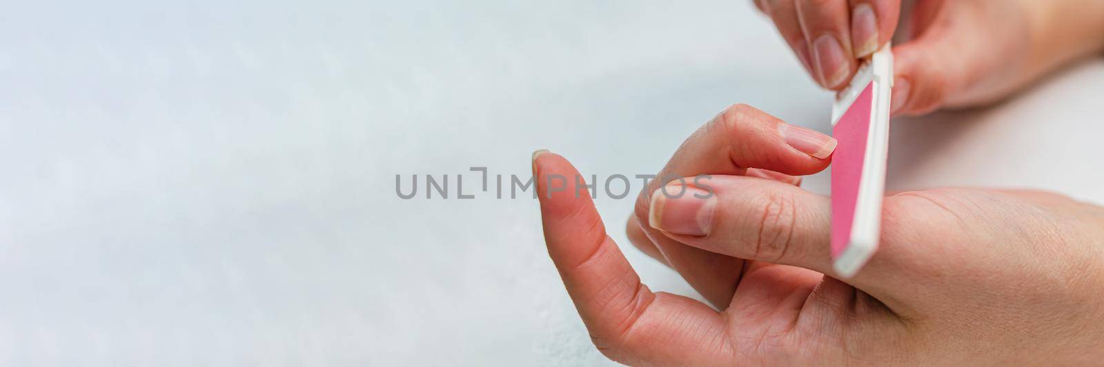 Woman doing manicure with nail file. Home nail care concept.