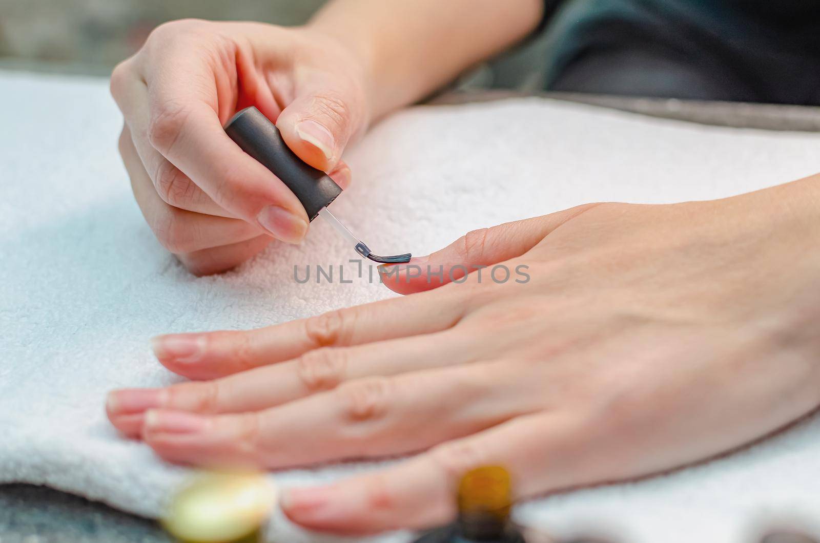 A woman applies a primer to her nails before applying varnish. Close-up of a hand