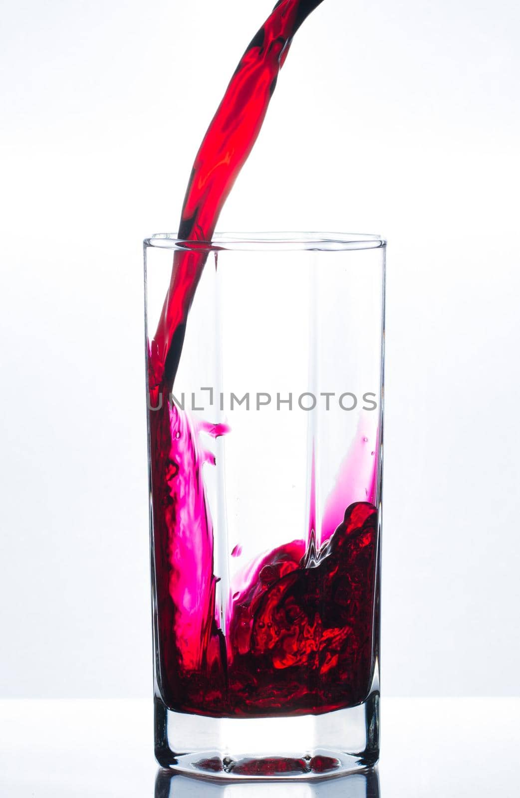 Pouring red juice in glass with bubbles