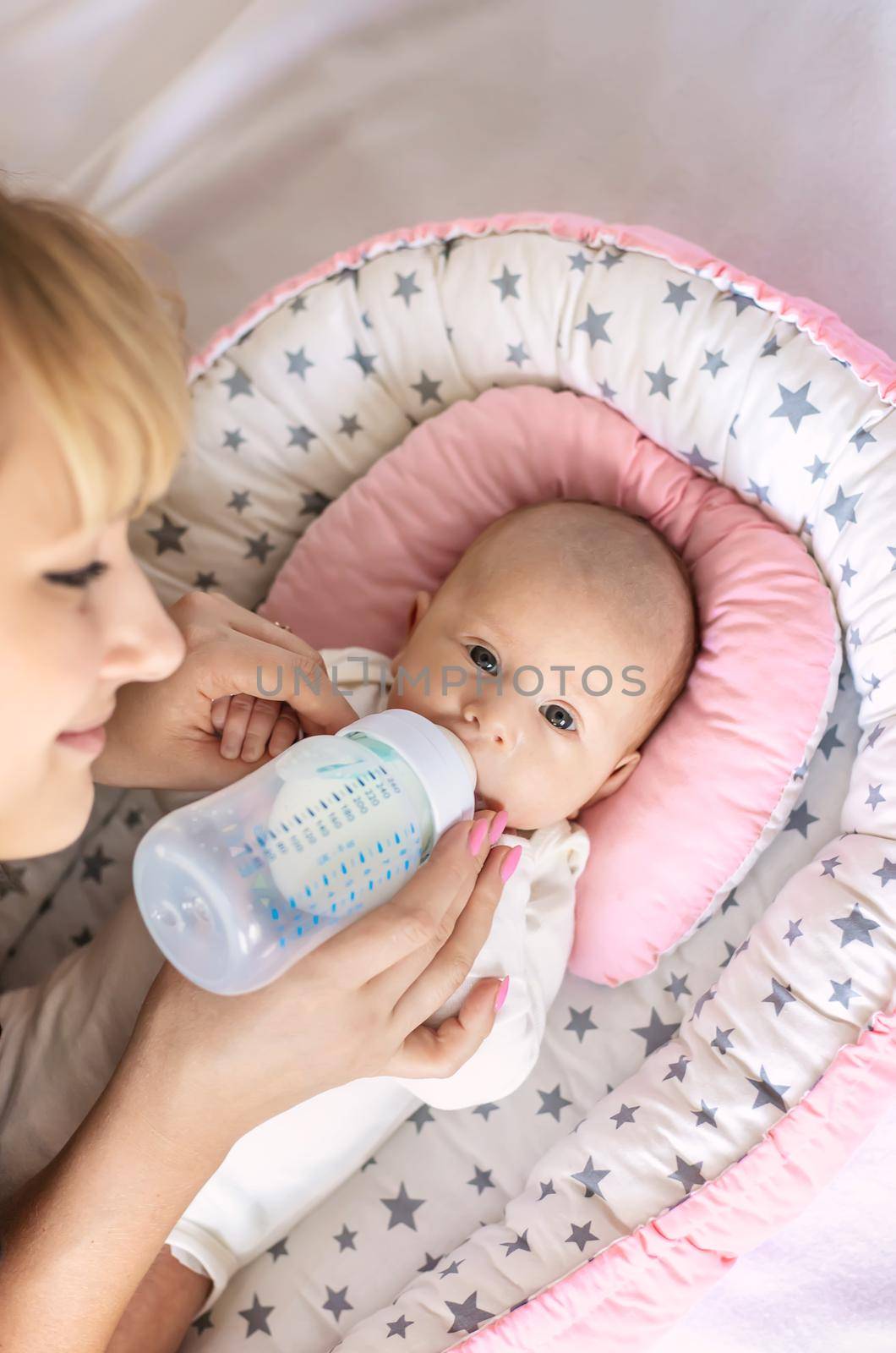 Mother feeds her newborn baby from a bottle. Selective focus. Food.