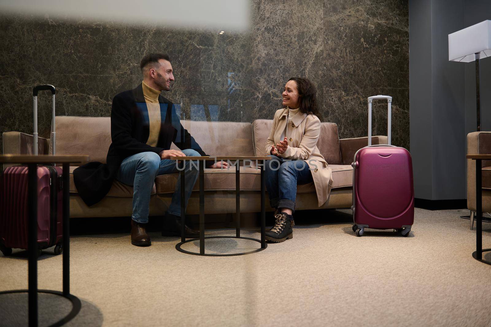 Married couple with suitcases, colleagues, team, partners on a business trip discussing plans and projects in a VIP lounge meeting room while waiting for flight in the airport departure terminal