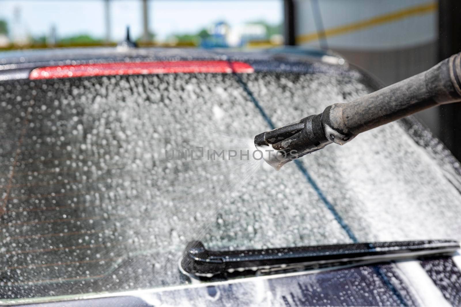 Car wash. The process of washing a car with active foam under pressure. Self-service manual car wash. Car care concept.