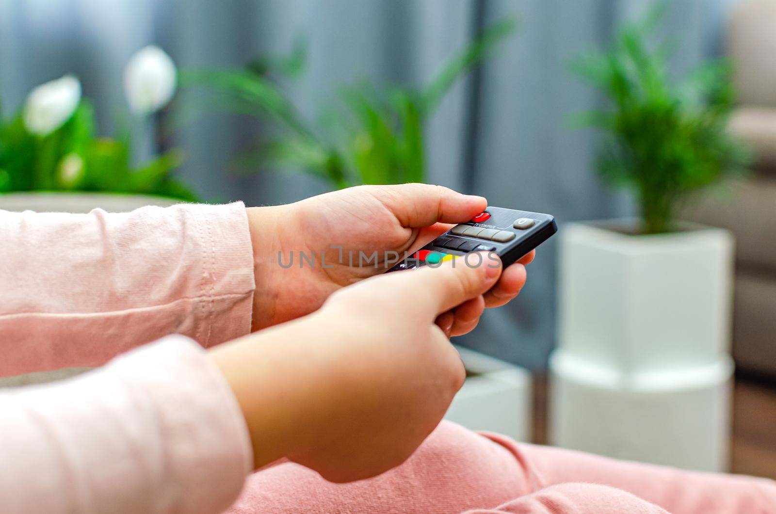 Little girl holding tv remote control at home.