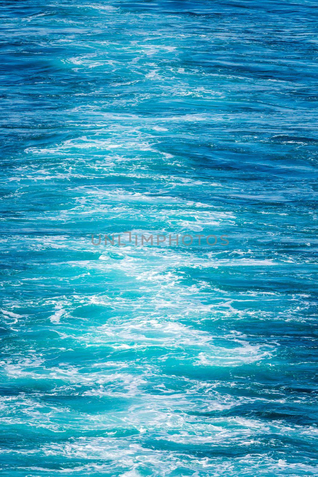 Blue water of the Pacific ocean behind cruise ship sailing in Alaska