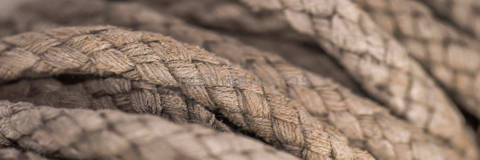 Thick tangled rope close up. Close-up of an old worn out boat rope as a nautical background. by SERSOL