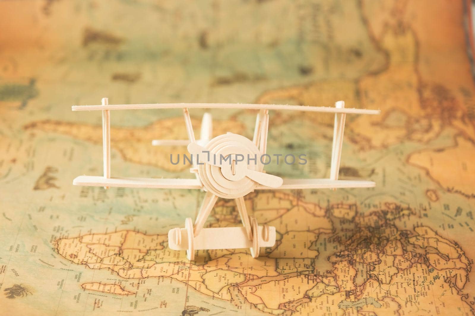 Wooden toy plane on world map on table. Travel and vacation concepts.