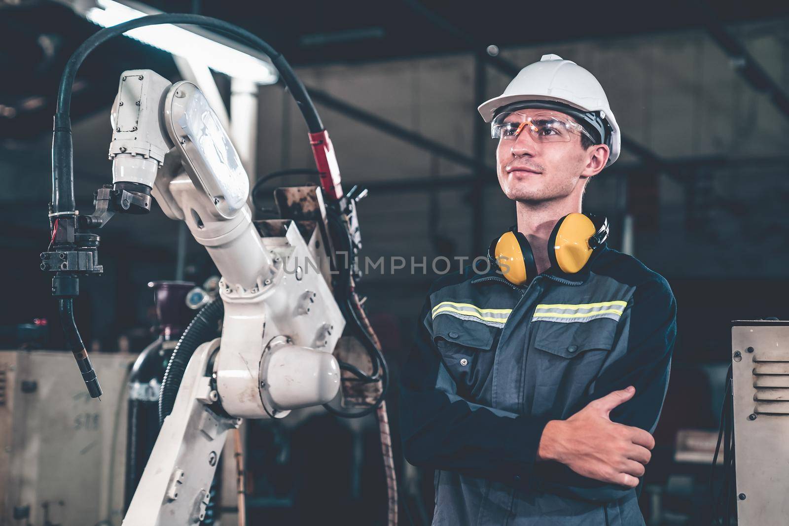 Young factory worker working with adept robotic arm in a workshop . Industry robot programming software for automated manufacturing technology .